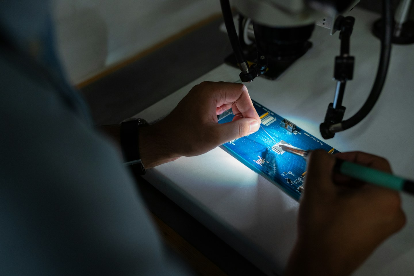 Technician working on an electronic board under inspection equipment